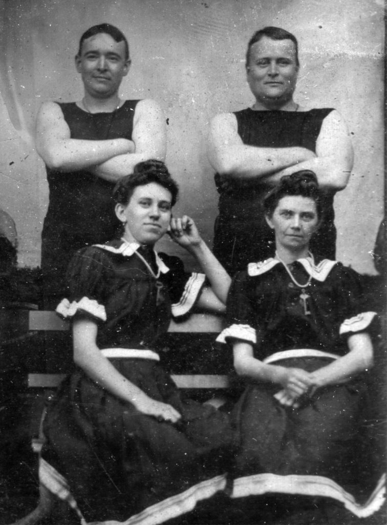 Black and white image of two men and two women in what appears to be bathing costumes.
